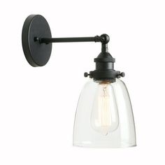 an industrial style wall light with clear glass shade and black metal fittings on the arm