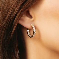 a close up of a person's ear wearing a pair of earrings with diamonds