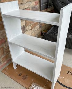 a white shelf sitting on top of a cardboard box in front of a brick wall