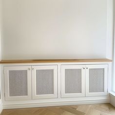 an empty room with a white cabinet and wood flooring on the side, next to a window