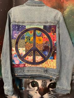 a denim jacket with a peace sign on it and a cat's face in the background