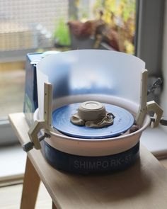 a blue and white container sitting on top of a wooden table next to a window