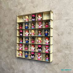 there are many small dolls in the toy display case on the wall behind the shelf