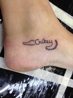 a small ankle tattoo with the word cheek written in cursive writing on it