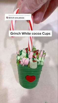 someone is holding a cup with candy canes and marshmallows in it