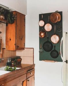 pots and pans hanging on the wall in a kitchen