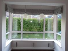 an open window in a room with white walls and windowsills, overlooking a garden