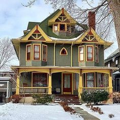 a green and yellow house with snow on the ground