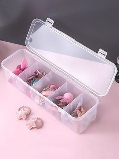 an open plastic box filled with lots of little toys on top of a pink table