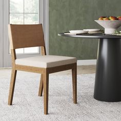 a dining room table with a bowl of fruit on it and a chair next to it