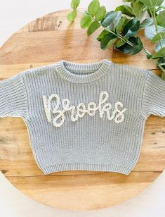 PERSONALIZED BABY, TODDLER & KID'S HAND EMBROIDERED KNIT SWEATER These customizable sweatshirts are such a beautiful piece to share with the littles in your life. They can also be used for pregnancy and birth announcements and, make an amazing baby shower or birthday gift too! ABOUT ME: *The lettering is unique to each sweatshirt and stencilled in the appropriate sizing. Each name is hand-embroidered with a high-quality wool yarn. *All items are hand-embroidered so no two designs are the same! Y Oversized Knit Tops With Letter Print, Playful Knitted Crew Neck Top, Playful Long Sleeve Customizable Tops, Customizable Cute Crew Neck Sweater, Cute Customizable Crew Neck Sweater, Fall Sweater With Name Print And Crew Neck, Fall Crew Neck Sweater With Name Print, Boys Embroidered Sweater, Baby Sweater With Name