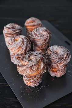 several pastries on a black plate with powdered sugar