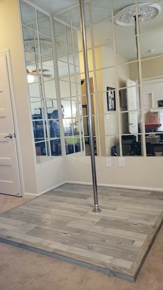 an empty room with mirrors on the wall and wood flooring in front of it