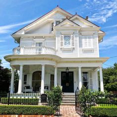 a large white house sitting on top of a lush green field next to a fence