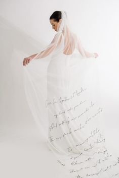 a woman in a wedding dress with a veil over her head and writing on the fabric