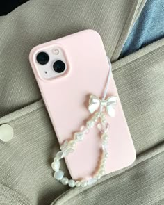 a pink phone case with pearls and a bow on the back, sitting on a suit jacket