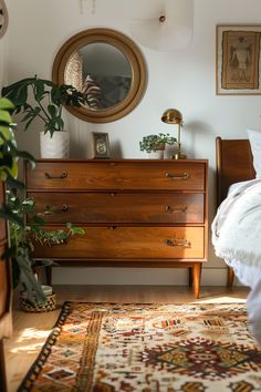 a bedroom with a dresser, mirror and plants on the side table in front of it