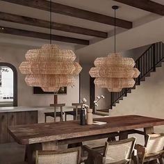 a dining room table with chairs and lights hanging from it's ceiling, next to a staircase