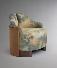 an upholstered chair with a wooden base and floral fabric on the armrests