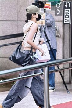 a woman walking down the street carrying a black bag