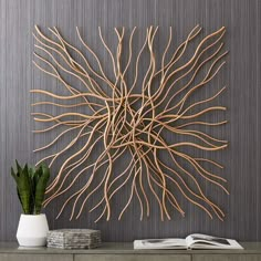 a wall sculpture made out of branches on top of a wooden table next to a potted plant