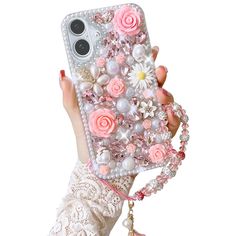 a woman holding up a phone case with flowers on the back and pearls around it