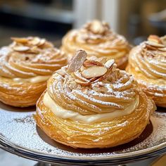 several pastries sitting on top of a silver plate covered in powdered sugar and nuts