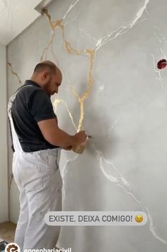 a man painting a wall with white paint and gold flecks on the walls