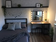 a bedroom with a bed, desk and mirror on the wall next to it is lit up by lights