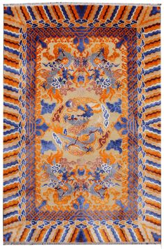 an orange, blue and yellow rug with dragon designs on the center is surrounded by wavy lines