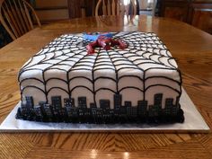 a spiderman cake sitting on top of a wooden table next to a dining room table