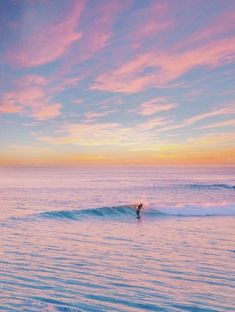 a person riding a wave on top of a surfboard in the ocean at sunset