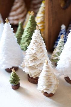 small white christmas trees are lined up on a table