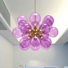 a purple chandelier hanging from the ceiling in a room with white walls and flooring