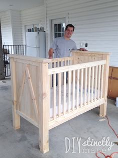 a man standing next to a wooden crib in the middle of a garage area