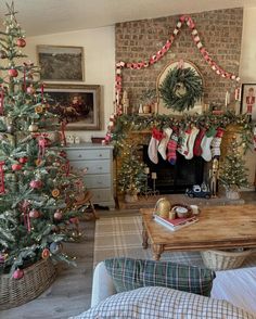 a living room decorated for christmas with stockings on the mantel and trees in baskets