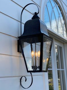 an old fashioned lantern hanging on the side of a house with three light bulbs attached to it