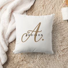 a white throw pillow with the word addson on it next to a pile of blankets