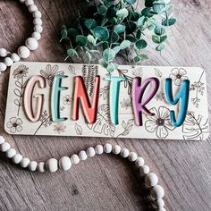 a wooden sign with the word gentry spelled in colorful letters and flowers on it