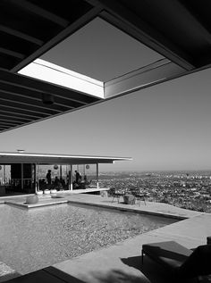 a black and white photo of an outdoor swimming pool with the city in the background