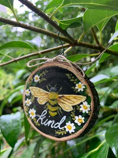 a bee painted on a piece of wood hanging from a tree