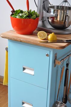 a kitchen island with a bowl of salad on top and utensils next to it