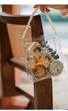 a person is holding a clear bag with various items in it on a wooden chair