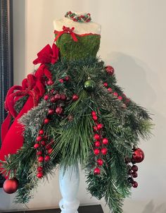 a white vase filled with christmas decorations and greenery