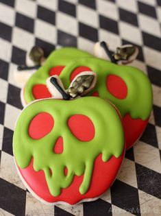 two decorated cookies sitting on top of a black and white checkered tablecloth covered in green icing