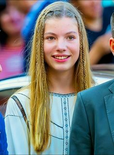 two people standing next to each other in front of a car and one person with long blonde hair