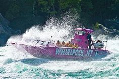 a pink boat with people in it is going through the water and splashing around