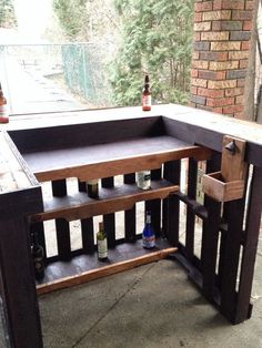 an outdoor bar made out of pallets with bottles on the top and bottom shelf