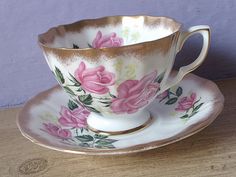 a tea cup and saucer with pink roses on it