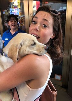 a woman holding a yellow dog in her arms